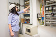 © Климов Максим - Female engineer in white helmet switches on circuit breakers in electrical box. Professional girl checks the switchboard of the enterprise. The specialist works in the electrical distribution panel.