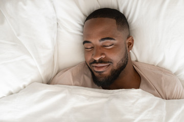 Calm biracial man sleeping seeing pleasant dreams