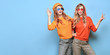 © evgenij918 - Two Lovable embracing fashionable woman sisters in Trendy orange yellow outfit. Carefree beautiful funny stylish friends smiling shows peace sign on blue. Happy fashion girl, colorful positive banner