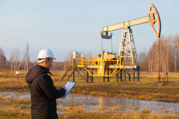 Engineer in a white helmet on an oil rig with a tablet. Oil production in Russia, Republic of Bashkortostan. Quality control. Oil production schedule