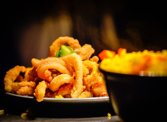 Deep Fried Calamari in White Plate. Mexican rice blurred at foreground.