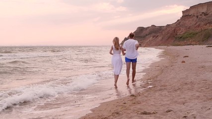 Canvas Print - Young couple having fun on beach at sunset