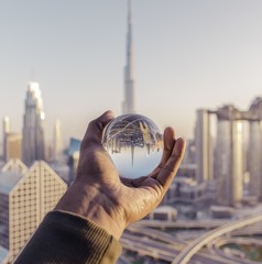 Poster - Closeup shot of a male hand holding a crystal ball with the reflection of the city