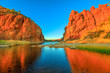 Northern Territory, Australian Outback. Scenic Glen Helen Gorge in West MacDonnell Ranges changes colours with sunrise light and reflects on waterhole in dry season at sunrise light.