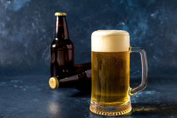 glass of cold beer and bottle on gray stone table