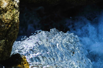 Close up motion wave of fresh clean and clear water flowing splash on the rock from waterfall