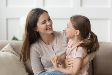 Wall Mural - Smiling young mom and daughter have fun laughing