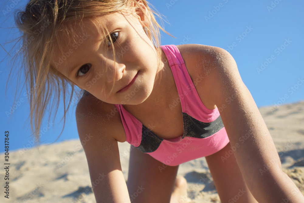 dziewczynka bawiąca się na plaży podczas letnich wakacji nad morzem  - obrazy, fototapety, plakaty 