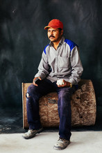 Studio Portrait Of Construction Worker Sitting On Old Barrel