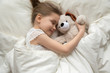 © fizkes - Preschooler girl hug teddy sleeping peacefully in cozy bed