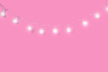 Christmas Ornaments On Pink Background. Festive Decorations, White Sparkling And Glowing Lights Garland. Traditional Winter Holiday Celebration Accessories. Xmas Backdrop With Copyspace