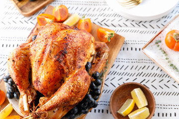 Roasted whole turkey on a table with persimmon, blue grape and lemon for family Thanksgiving Holiday.