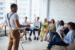 © alfa27 - Ambitious young caucasian coach leader give presentation to co-workers sitting listening to him in modern office
