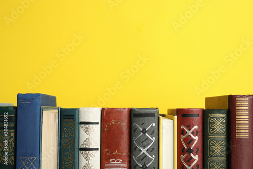 Fotomural Collection of old books on yellow background, space for text