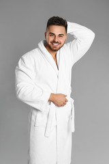 Wall Mural - Happy young man in bathrobe on grey background