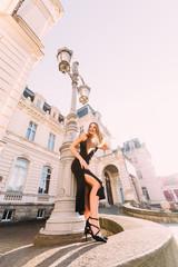 Wall Mural - girl in stylish black dress posing near street lamp on the backg