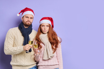 Beautiful sweet couple looking at camera with upset faces, raising hands with champagne, clinking glasses, drinking alcohol, expressing disappointment, tired of celebration