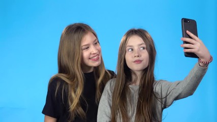 girls taking selfie, smiling, posing, looking at photos on smartphone.