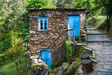 Old Rustic Stone House With Bright Blue Doors And Windows In A Lush Forest Landscape In A Village In Portugal