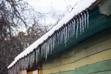 Icicles On Snow Covered Roof Of A Village House In The Winter