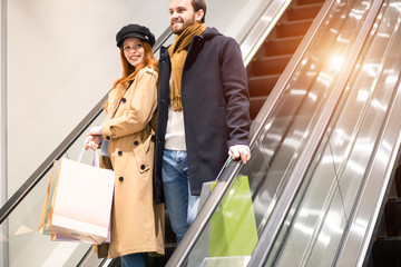 caucasian redhaired woman and bearded man smile, enjoy shopping together, happ after buying new clot