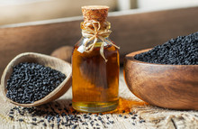 Glass Bottle Of Black Cumin Seeds Essential Oil , Nigella Sativa In Spoon On Wooden Background. Organic Herbal Medicine For Many Diseases, Black Cumin