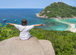 © Soonthorn - Woman sitting on stone high cliff raising hands open arms achievements celebrate enjoy to landscape view after climbing to the peak of the hill  at Koh Nang Yuan Island ,Surat Thani, Thailand summer h