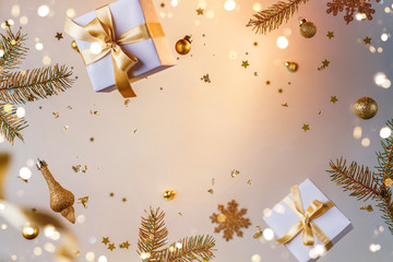 Wall Mural - Merry Christmas and New Year background. Xmas holiday card made of flying decorations, gold fir branches, balls, snowflakes, sparkles, gift boxes, bokeh, light on golden background. Selective focus