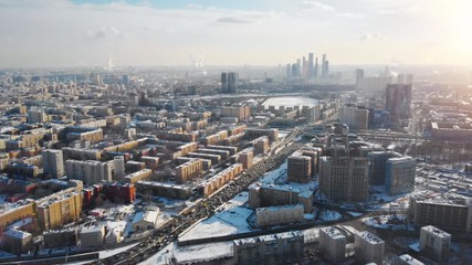 Wall Mural - Beautiful aerial panorama of Moscow on sunny winter day. Picturesque view from above on the city covered with snow and lit by the sun, with buildings, traffic and Moscow City Business Center far away.