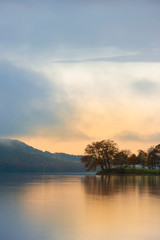 stuning autumn fall sunrise landscape over coniston water with mist and wispy clouds