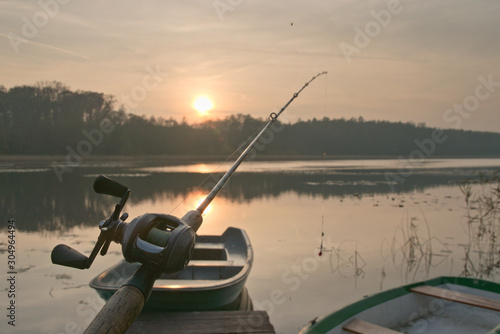 Fotomural Fishing boat in marina during sunset and fishing reel and rod