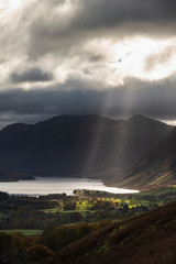 Wall Mural - Majestic sun beams light up Crummock Water in epic Autumn Fall landscape image with Mellbreak and Grasmoor