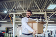 © Dusan Petkovic - Smiling caucasian bearded graphic engineer in shirt and tie walking in printing shop and relocating box. In background are printing machines.