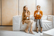 © rh2010 - Two female colleagues having fun conversation, sitting together on the couch during a coffee break in the office