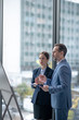 © zinkevych - Couple of business partners standing near window and talking about new project