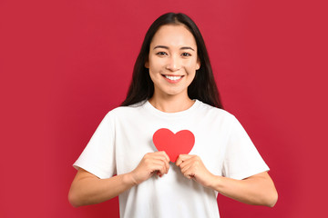 Wall Mural - Beautiful young Asian woman with paper heart on color background