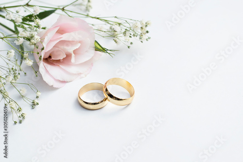 Fotomural Pink flowers and two golden wedding rings on white background.