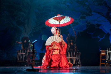 Wall Mural - Traditional Japanese performance. Actress in red with umbrella and fan dancing turning.