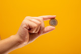 Fototapeta  - Hand holding one Real coin of Brazil on yellow background. Finance concept.