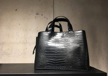 Black Leather Mock Croc Tote Bag On Shelf. Woman Elegant Handbag With Two Handles In A Showcase Of A Luxury Store On A Concrete Background. Fashion Women Accessories. Fashion Concept