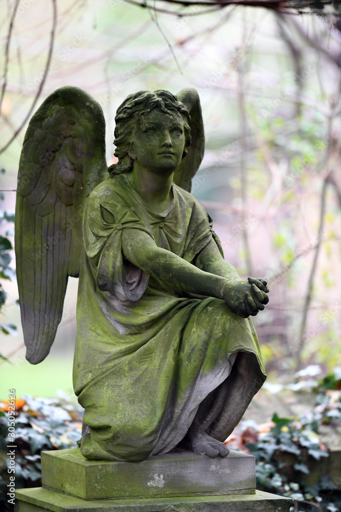An old, weathered sandstone Sculpture of an angel with spread wings. A ...