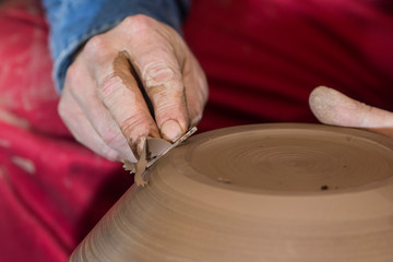 Professional male potter making ceramics on potters wheel in workshop, studio. Close up shot of potters hands. Handmade, art and handicraft concept