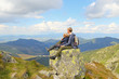 © endostock - Mother and daughter sitting on large stone and watching mountain view