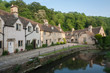 © LAURA - CASTLE COMBE, COTSWOLDS, UK - MAY 26, 2018: Street view of old riverside cottages in the picturesque Castle Combe Village, Cotswolds, Wiltshire, England - UK