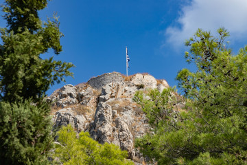 Wall Mural - Greek flag and ruins over a mountain in Hydra Island