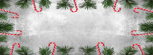 Christmas Background Panorama Banner Long - Frame Made Of Sweet Candy Canes And Pine Branches Isolated On Gey Concrete Stone Texture - Top View With Space For Text