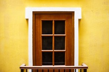 Closeup Of A Wooden Door With Windows On A Yellow Wall