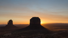 Sun Rising Behind The Merrik Butte And The Mitten Butte In Monument Valley