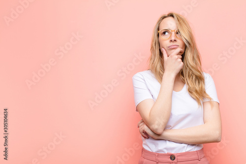 Fotomural young pretty blonde woman thinking, feeling doubtful and confused, with differen