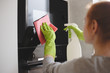 Woman cleaning oven and microwave with rag in kitchen, close up